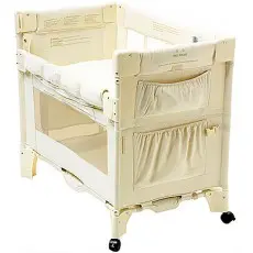 A white crib with wheels and a pillow.